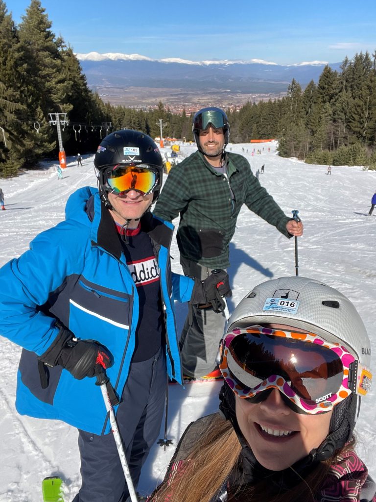 three friends wearing goggles and helmets on a beginner ski slope in Bansko