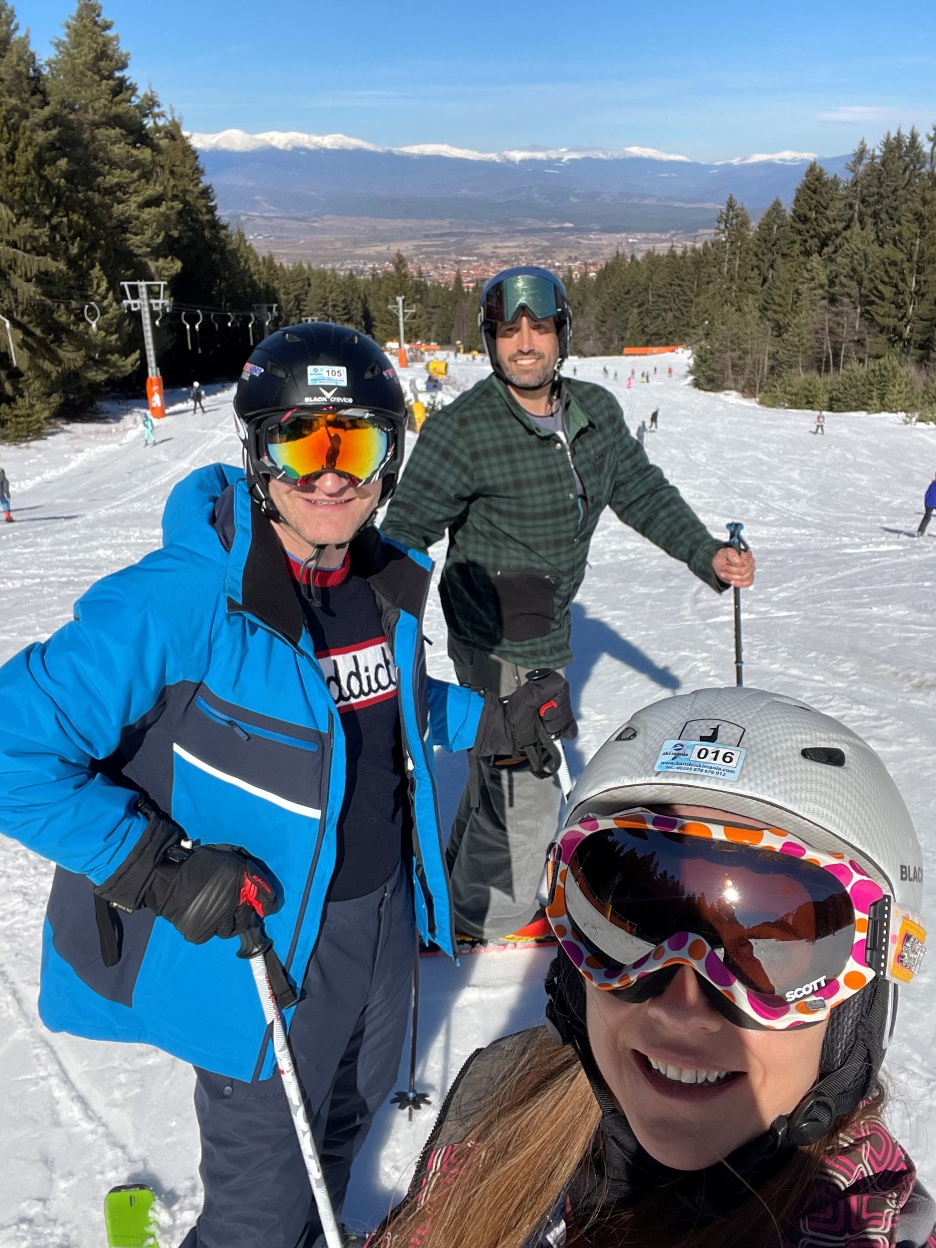three friends wearing goggles and helmets on a beginner ski slope in Bansko