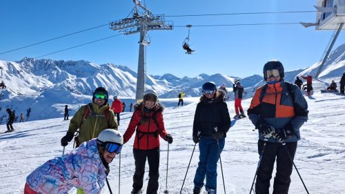 A group of friends on a ski trip standing in front of a chairlift on the slopes in Bansko