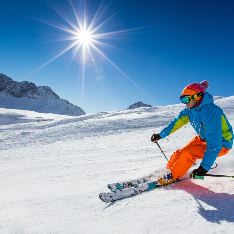 a skier skiing on Bansko slopes with clear skies and a bright sun