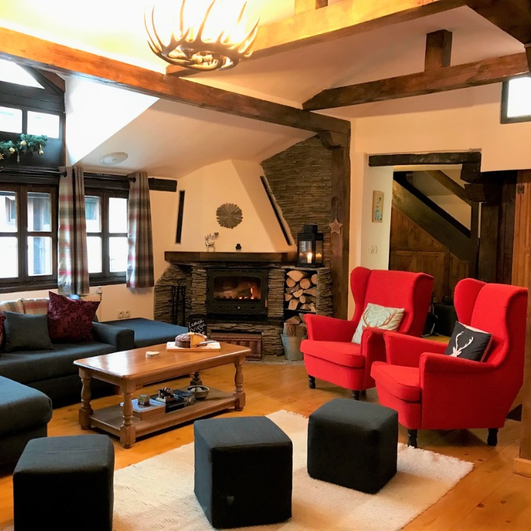 red armchairs, black sofa, and a log fire in the lounge of a ski chalet