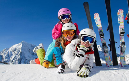 A family playing in the snow wearing ski gear